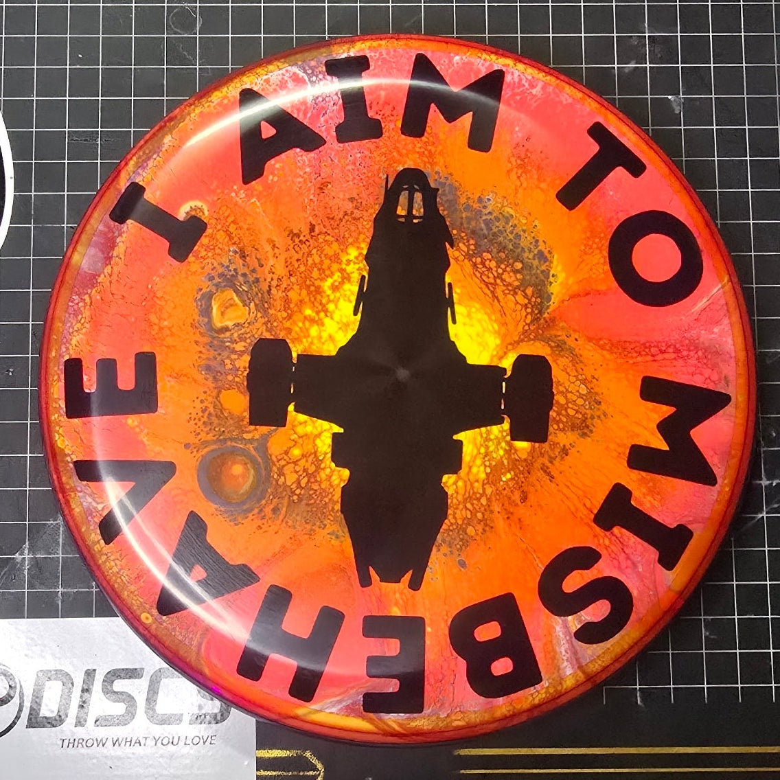 Button badge with 'I Aim to Misbehave' text and silhouette on a branded background